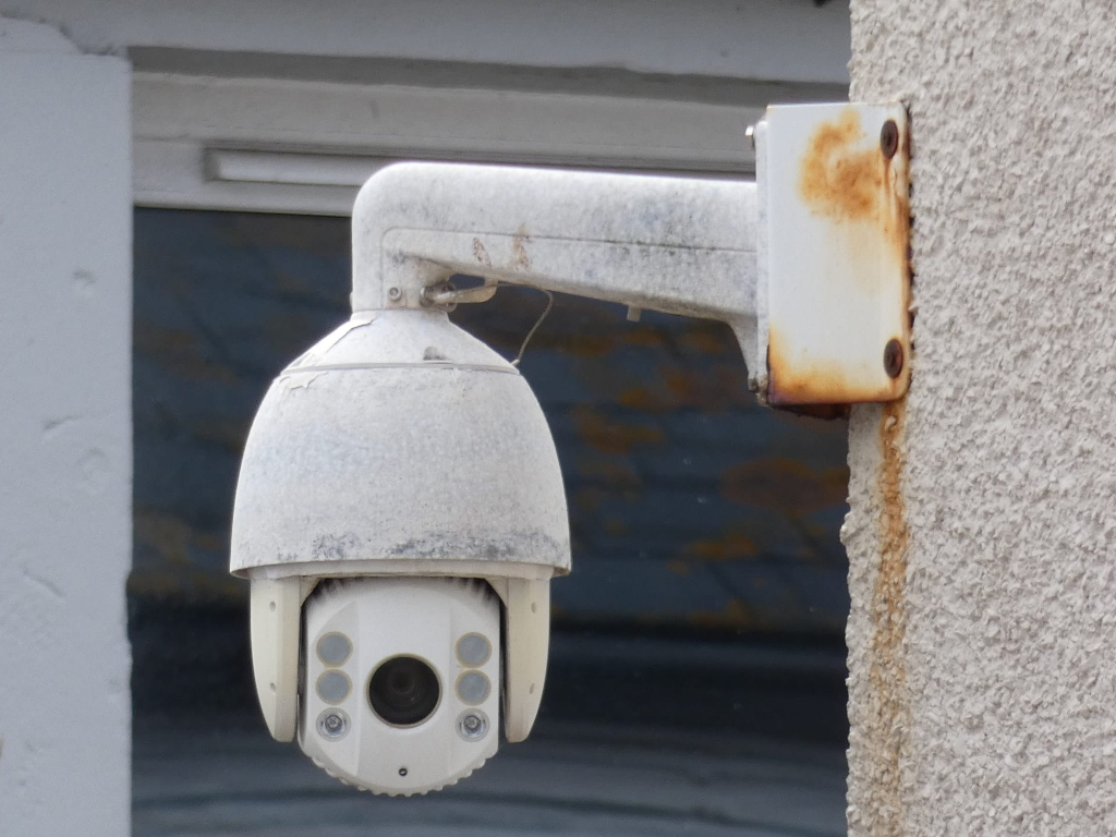 rusted white cctv camera watches us from above